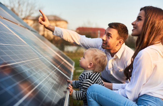 Famille heureuse à côté d'un panneau solaire installé dans un jardin de maison