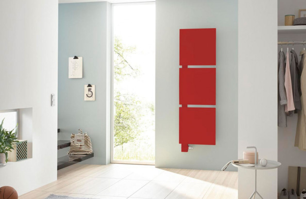 Radiateur rouge vertical installé sur un mur près de la porte d'entrée