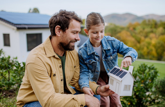 Famille découvrant une maison avec panneaux solaires pour production d’énergie en autoconsommation.