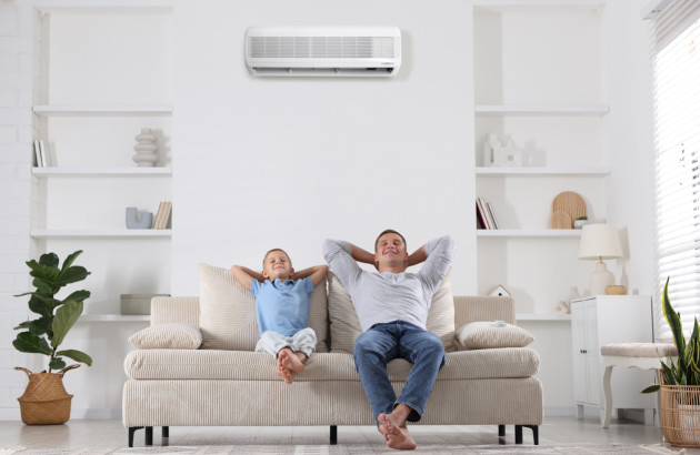 Famille détendue dans un salon lumineux équipé d’une climatisation murale réversible.