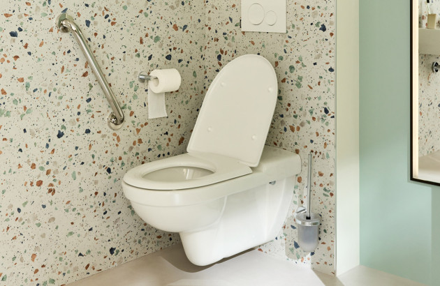 WC suspendu PMR avec barre de maintien dans espace sanitaire accessible.