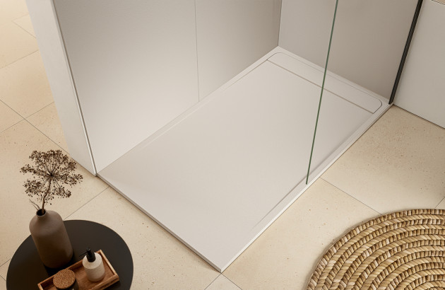 Douche contemporaine avec paroi en verre et colonne dorée dans une salle de bains minimaliste élégante.