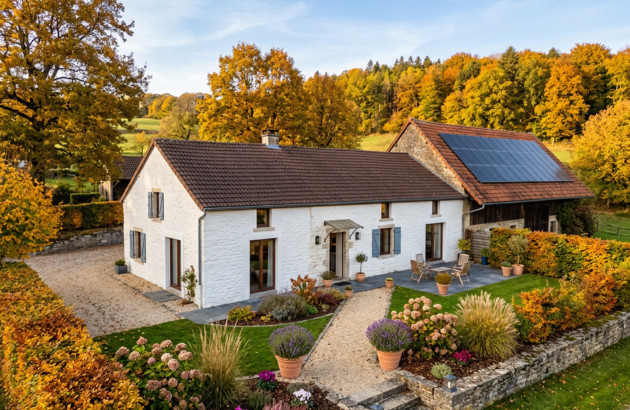 Maison rénovée avec panneaux solaires sur toiture dans un paysage automnal