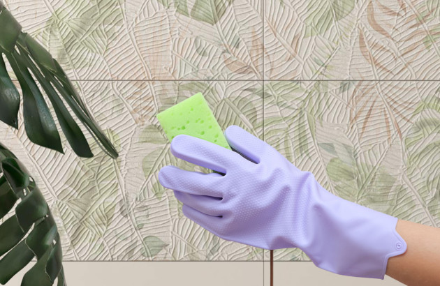 Femme qui passe l'éponge sur ses carreaux de carrelage effet feuilles