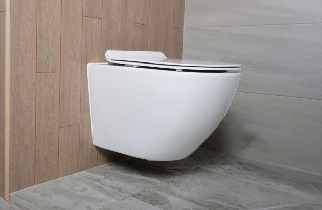 WC suspendu sans bride en céramique blanche, fixé au mur avec abattant fin, installé dans une salle de bains moderne au carrelage bois et gris, offrant un design épuré et un nettoyage facilité du sol.