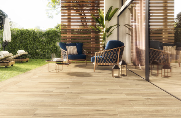Terrasse en carrelage effet bois avec mobilier de jardin tressé et ambiance chaleureuse.