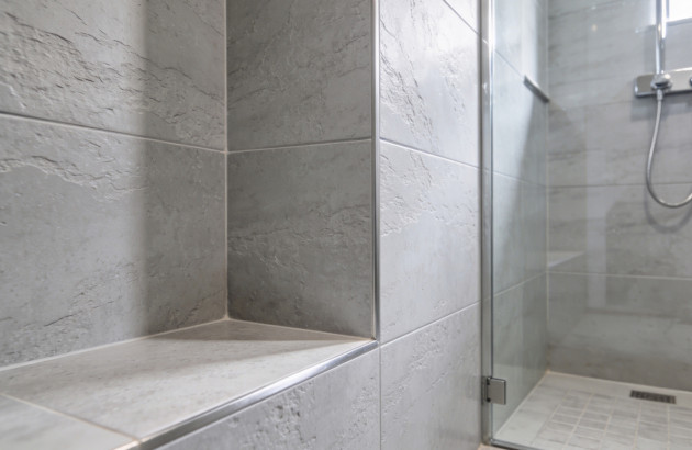 Détail d’une assise carrelée intégrée dans une douche à l’italienne