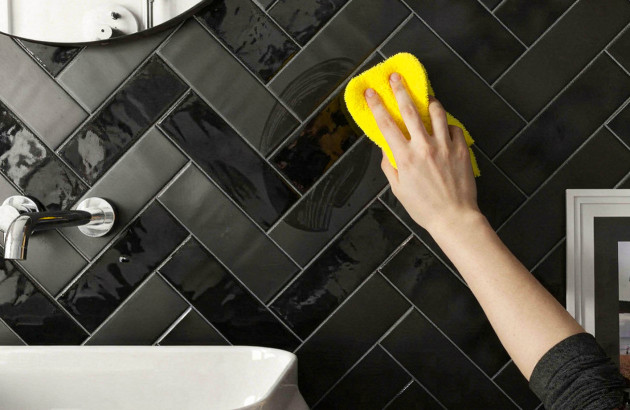 Nettoyage d’un mur en zellige noir brillant avec une éponge.