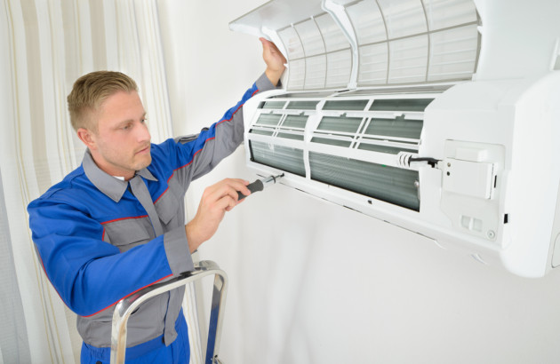 Technicien réalisant l’entretien d’un climatiseur mural