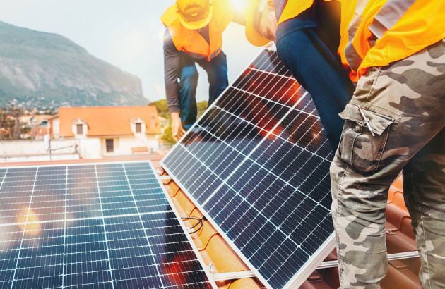 Artisans qui installent des panneaux solaires sur un toit avec des tuiles