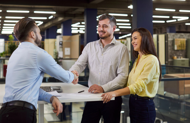 Couple échangeant avec un conseiller en showroom pour choisir un projet de carrelage.