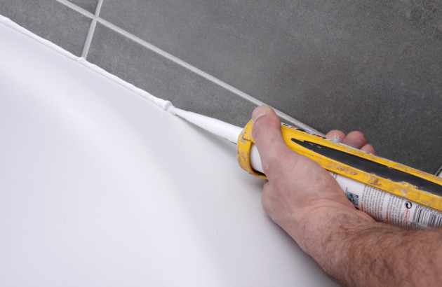 Application de joint silicone pour assurer l’étanchéité autour du receveur de douche.