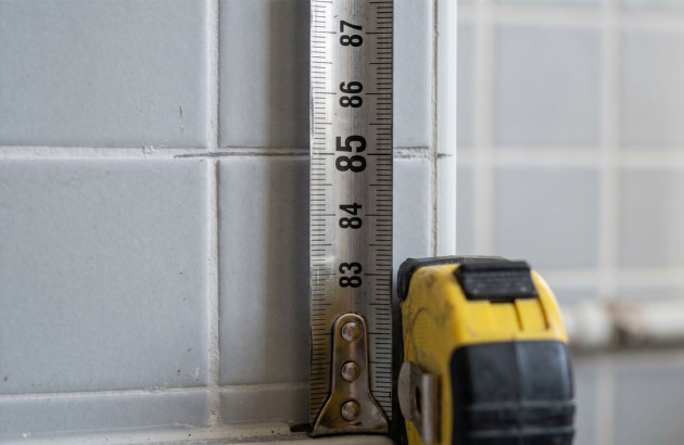 Prise de mesures sur un mur carrelé avant l’installation d’un meuble de salle de bains.