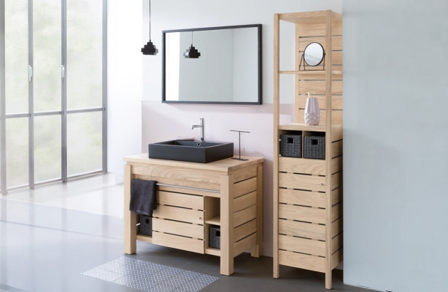 Meuble de salle de bains en bois clair avec vasque à poser et colonne de rangement assortie.