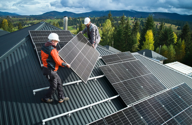 Pose de panneaux solaires sur toiture par des professionnels avec vue sur paysage rural.
