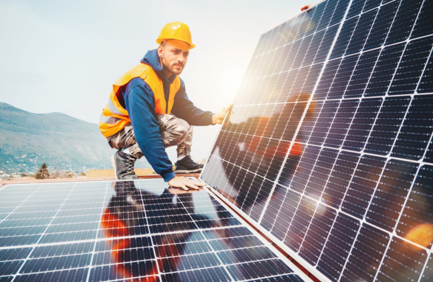 Homme sur un toit en train d'installer des panneaux solaires