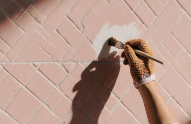 Personne avec des gants qui peint des carreaux de carrelage en blanc