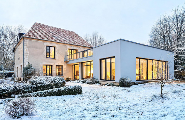 Maison ancienne rénovée avec extension contemporaine dans un environnement hivernal enneigé.