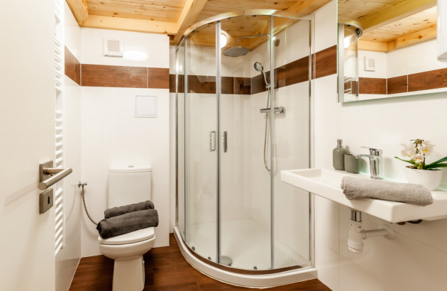 Salle de bains compacte avec douche d’angle, meuble vasque et finitions bois chaleureuses.