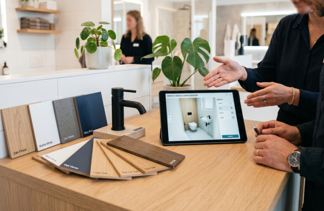 Femme qui conseille un client en showroom Espace Aubade via une tablette et un outil de simulation