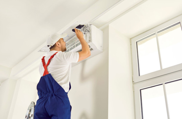 Homme qui intervient sur la maintenance d'un climatiseur