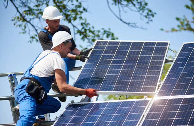 Deux artisans qui installent des panneaux solaires sur un support métallique