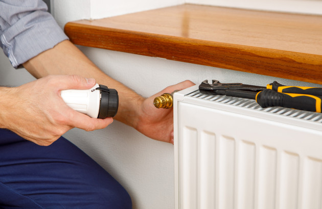 Homme qui intervient sur le thermostat d'un chauffage