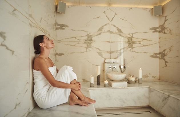 Femme qui est assise dans son hammam carrelé de couleur claire