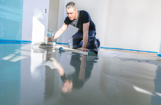 Homme qui applique du ragréage autolissant sur un sol intérieur