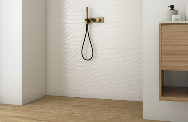 Douche moderne avec carrelage relief blanc et robinetterie encastrée noire et dorée.