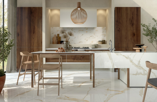 Cuisine moderne et chaleureuse avec carrelage effet marbre blanc veiné d’or, mobilier en bois et grand îlot central.