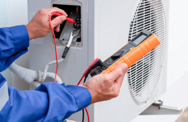 Homme artisan qui réalise un test électrique sur une pompe à chaleur