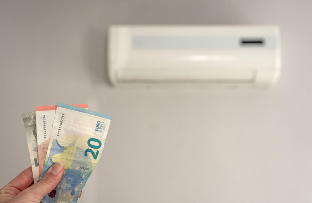 quelqu'un qui tient des billets en euros devant un climatiseur mural blanc