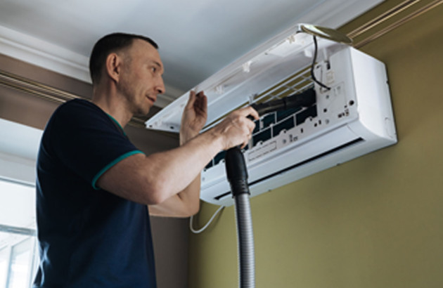 Homme qui nettoie son climatiseur
