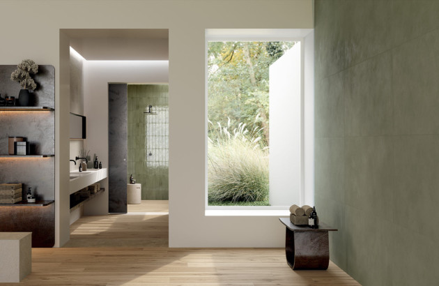 Salle de bains naturelle et apaisante avec carrelage vert doux, mobilier suspendu et vue sur le jardin.