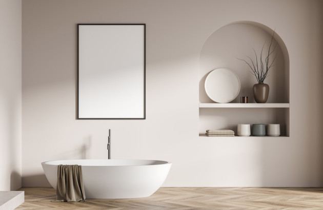 Salle de bains minimaliste avec baignoire îlot, niche murale décorative et tons beiges.