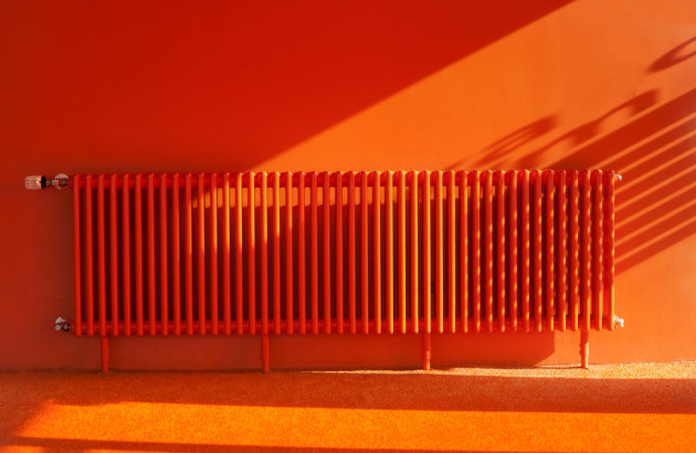 Chauffage central orange sur un mur de la même couleur