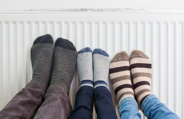 Famille qui se réchauffe les pieds devant un radiateur