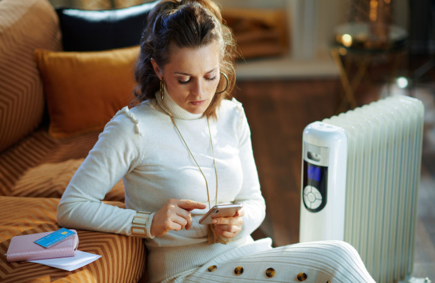 Femme assise à côté du radiateur tenant son téléphone