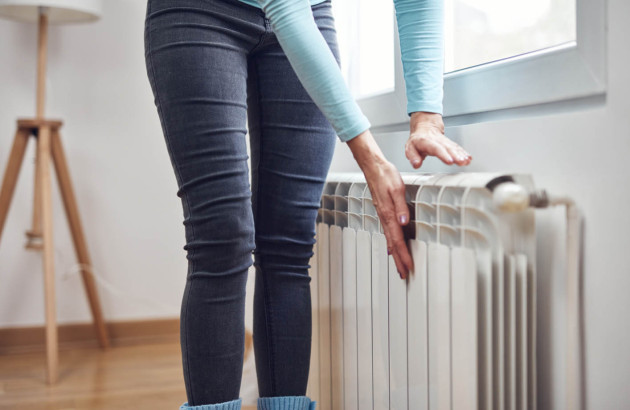 Femme chauffant ses mains sur le radiateur pendant les froides journées d'hiver.