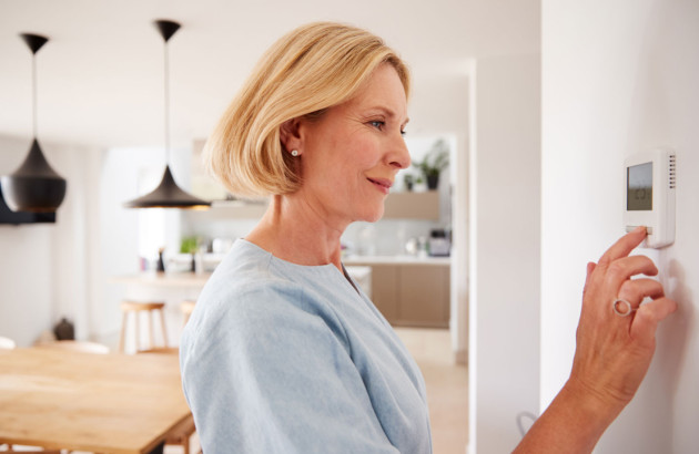 Femme en train de manipuler son thermostat d'ambiance