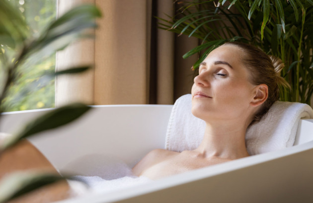 Femme en train de savourer son bain dans une salle de bains biophilique