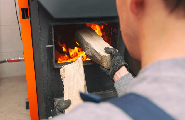 Homme alimentant une chaudière à bois de bûches