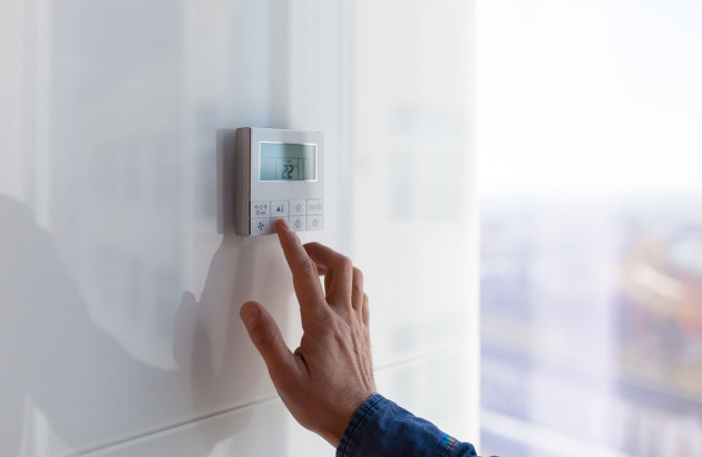 Main manipulant un thermostat d'ambiance