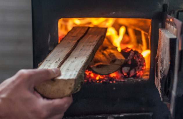 Personne alimentant son poêle à bois de bûche