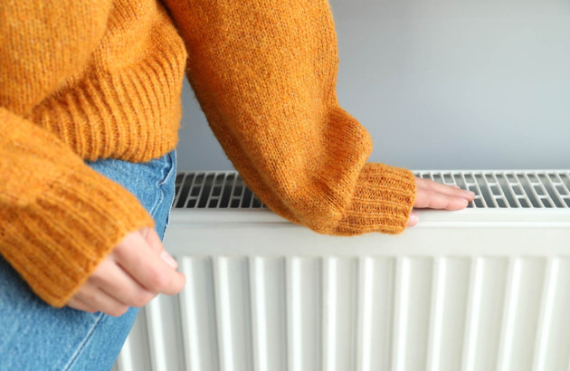 Personne assise sur un radiateur pour se chauffer
