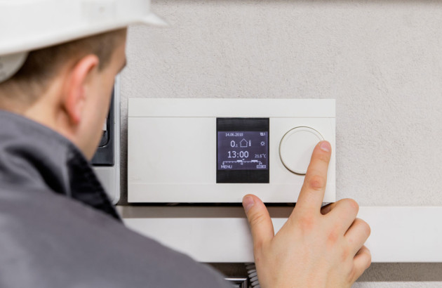 Personne en train de manipuler un thermostat d'ambiance