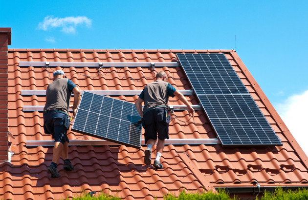 Deux personnes installant des panneaux solaires sur le toit