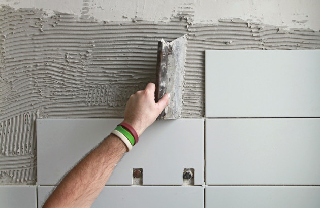 Professionnel en train de poser du carrelage blanc mural