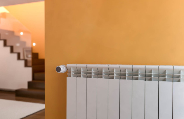 Radiateur posé sur un mur ocre jaune d'une entrée